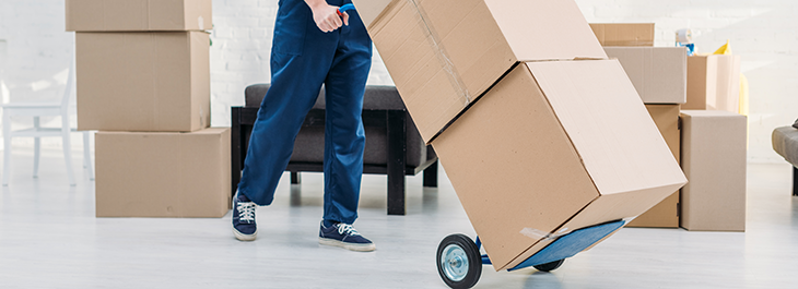 A mover is moving cardboard boxes using a dolly